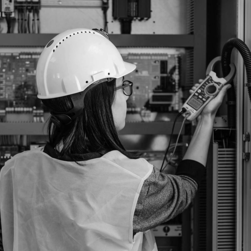 Young female maintenance engineer testing voltage with digital multimeter
